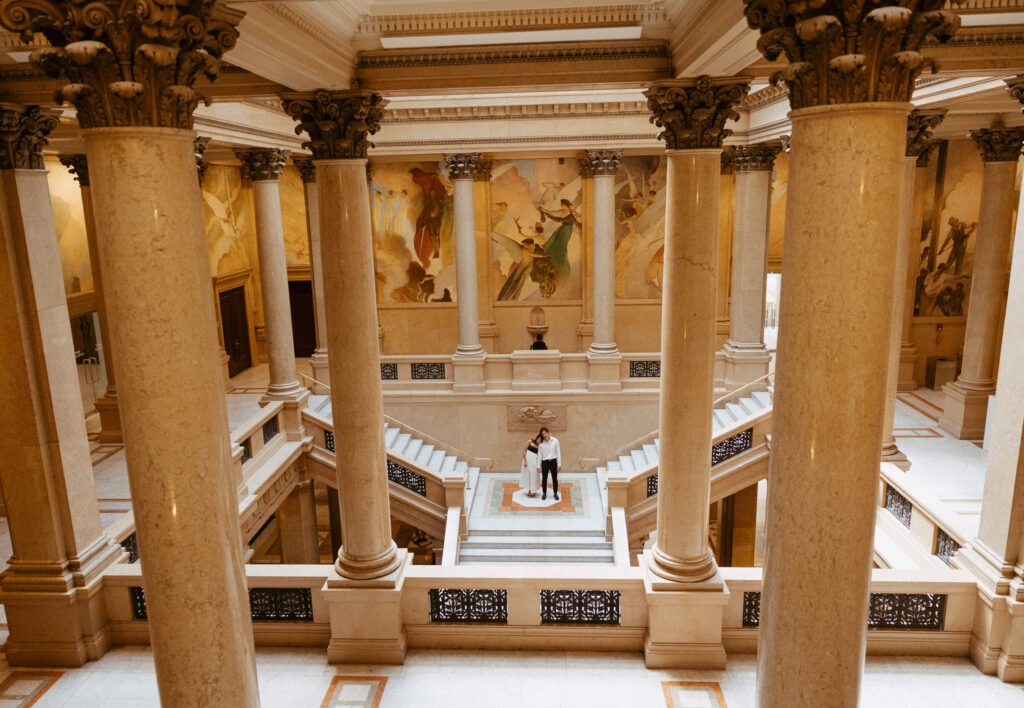 couple standing in grand staircase at carnegie museum of art photographed by pittsburgh engagement photographer