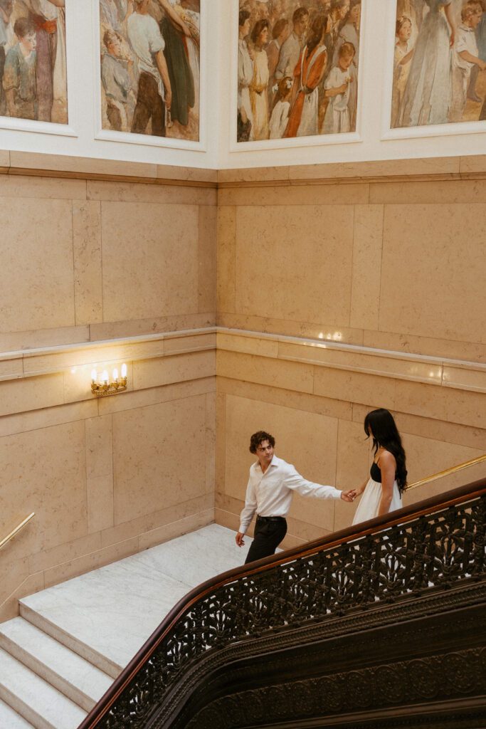 couple walking down grand staircase at art museum in pittsburgh taken by pittsburgh wedding photographer