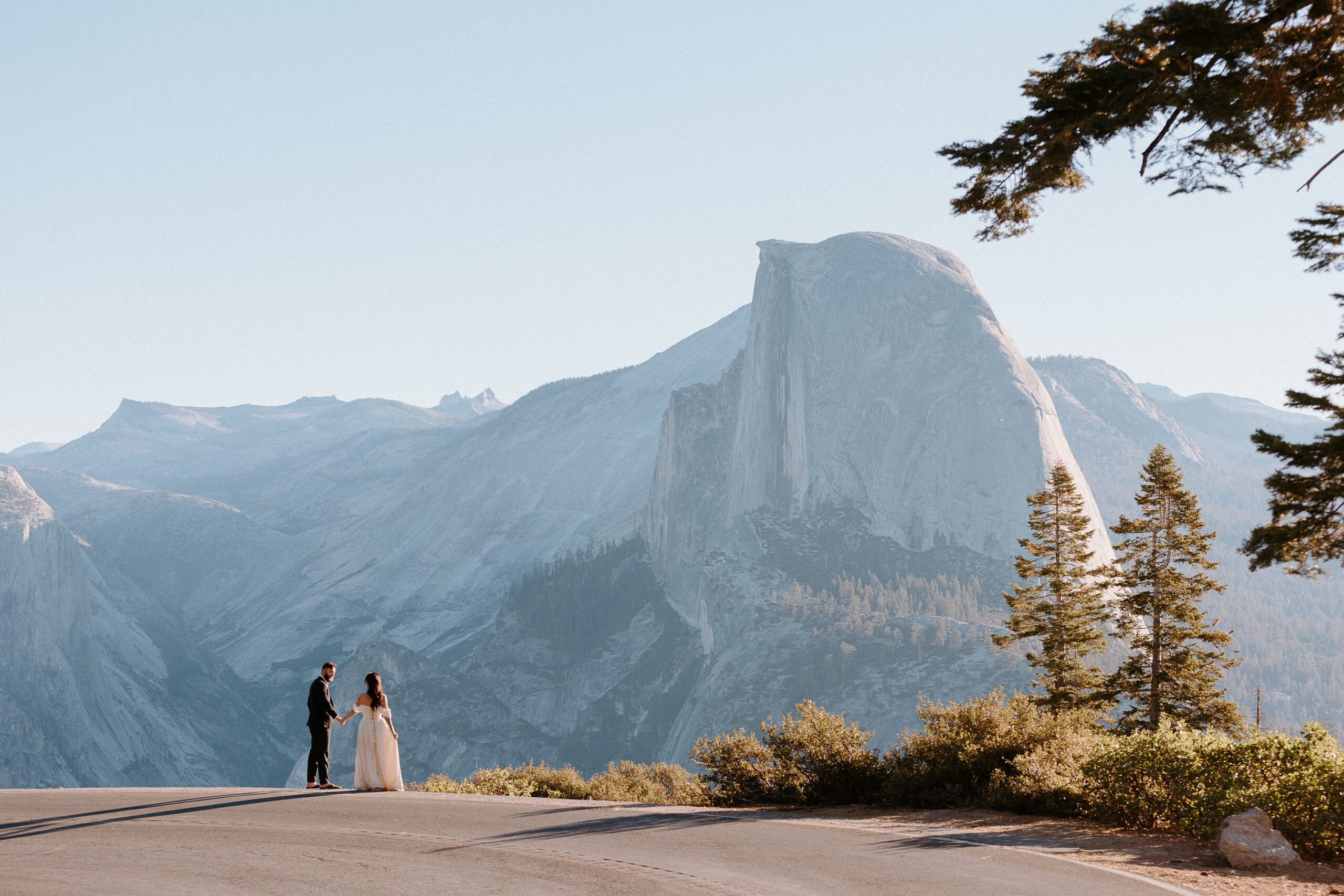 a couple at glacier point standing in front of half dome taken by yosemite elopement photogapher