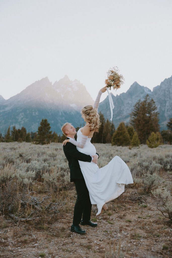 Grand Teton elopement couple celebrating and dancing in front of a mountain.