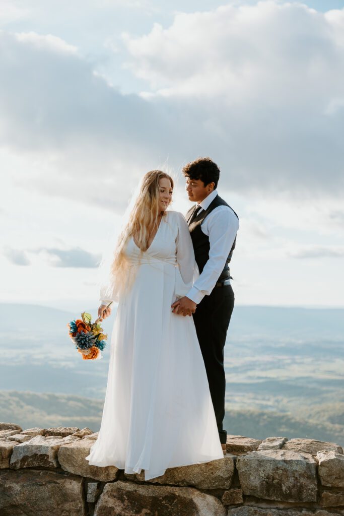 Couple standing on overlook wall during sunset in Shenandoah.