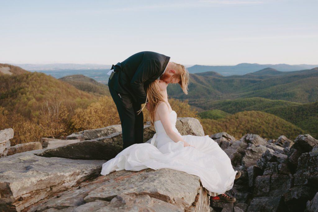 Groom leaning down to kiss bride on the summit of Blackrock Summit in Shenandoah National Park