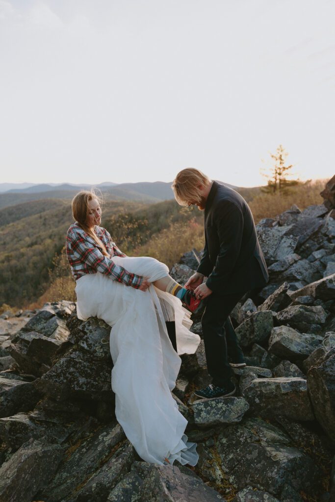 groom tying brides hiking boot during hiking elopement in virginia