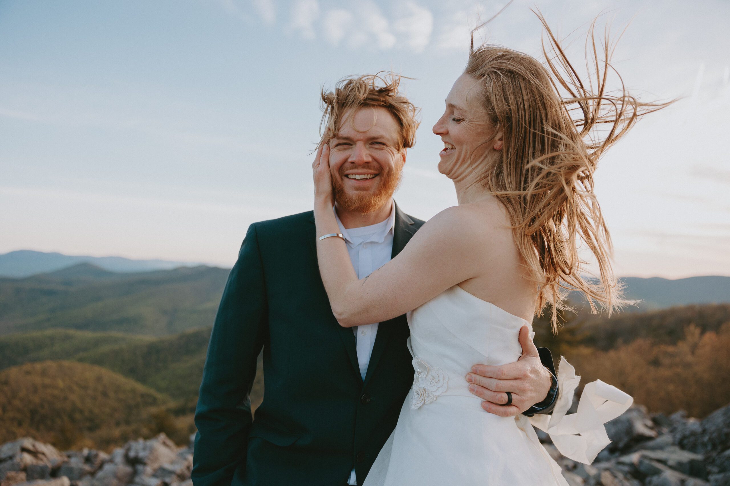 bride fixing grooms hair on windy summit in shenandoah national park