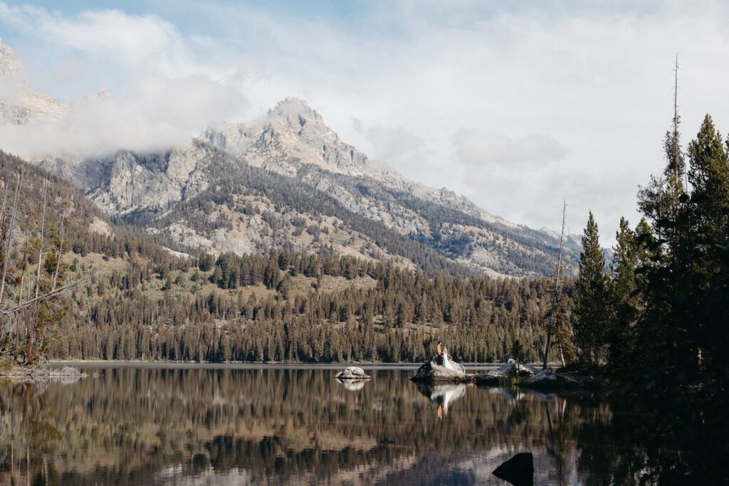 Bride and groom standing on a rock at Taggart Lake in Grand Teton National Park during their full day Jackson Hole elopement